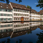 Domherrenhäuser spiegeln sich im Brunnen am Münsterplatz in Basel, Schweiz, Europa | Minster square buildings reflected in a fountain, Basel, Switzerland, Europe