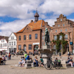 Tine Statue des Asmussen-Woldsen-Denkmal oder Tine-Brunnen vor den Häusern der Altstadt am Markt in Husum, Kreis Nordfriesland, Schleswig-Holstein, Deutschland, Europa | Tine Statue of the Tine-Well or Asmussen-Woldsen Monument and the historic buildings of the Old Town market sqaure in Husum, district of North Frisia, Schleswig-Holstein, Germany, Europe