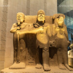 Statuengruppe mit Pharao Ramses II., Schöpfergott Ptah und der Löwengöttin Sekhmet im Grand Egyptian Museum in Gizeh, Ägypten, Afrika | Statue of God Ptah, King Ramesses II and Goddess Sekhmet, Grand Egyptian Museum, Giza, Egypt, Africa